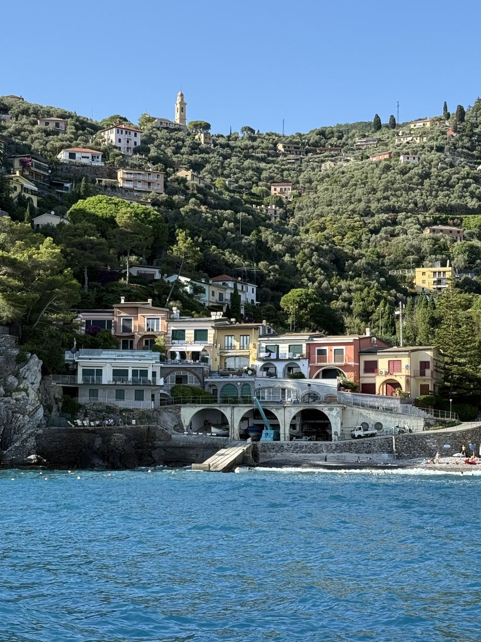 Le case del condominio viste dal mare, con gli archi del ricovero, il bigo e il campanile sulla collina